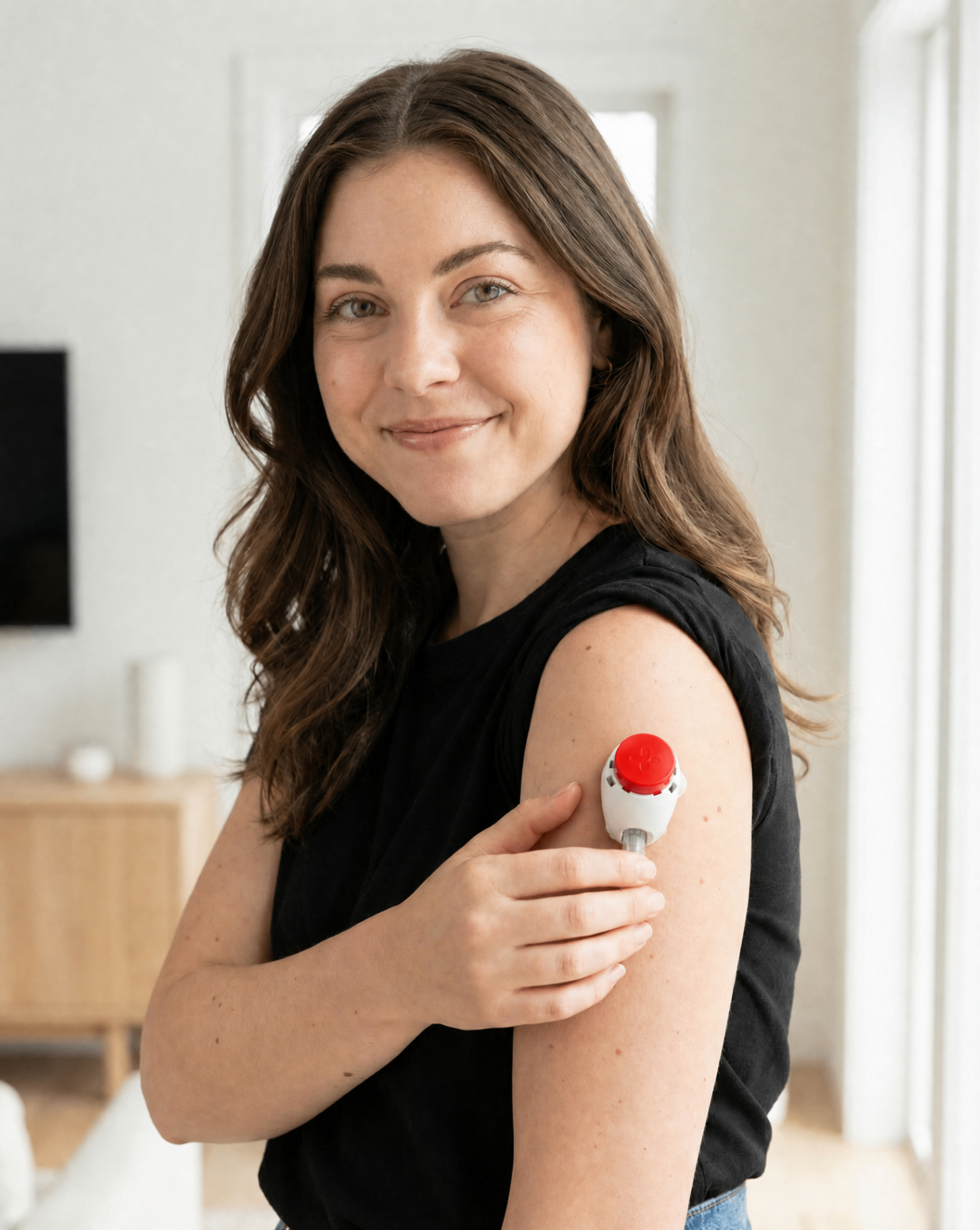 Woman wearing the Tasso at-home blood collection device on her upper arm in a bright kitchen